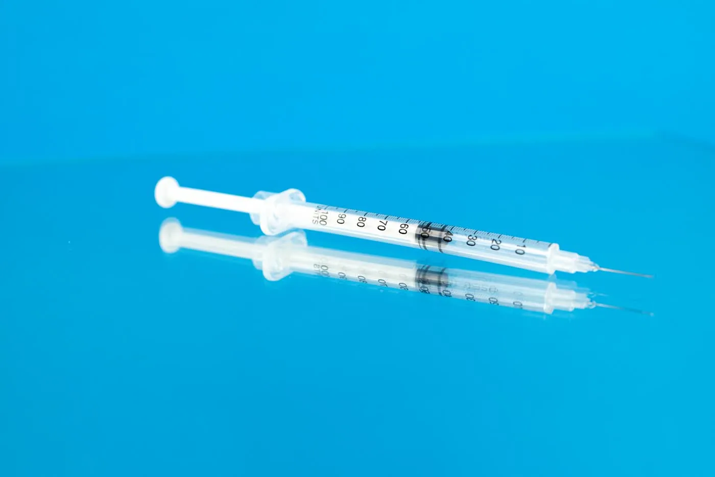 Feine Spritze mit hauchdünner Nadel auf blauem Grund — Mikro-Injektionen bei der Botulinumtoxin-Behandlung gegen Schwitzen